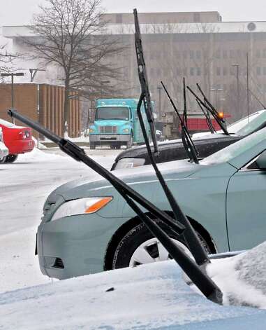 A row of cars have their windshield wipers up for easier cleaning behind a