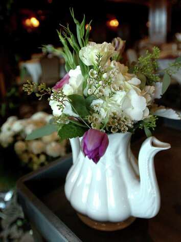 Tamera Menges places flowers in a tea pot for a tea party themed wedding 