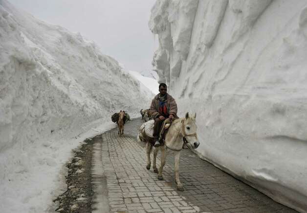 Kashmiri porters on horseback travel past walls of snow along the newly 
reopened Srinagar-Leh highway in Zojila, about 67 miles east of 
Srinagar, on Wednesday. The 275-mile-long highway was opened for the 
season by Indian Army authorities after remaining snow at Zojila Pass, 
some 11,581 feet above sea level, had been cleared. The pass connects 
Kashmir with the Buddhist-dominated Ladakh region, a famous tourist 
destination among foreign tourists for its monasteries, landscapes and 
mountains. AFP PHOTO/Tauseef MUSTAFA Photo: TAUSEEF MUSTAFA, AFP/Getty Images / 2012 AFP