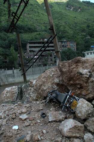 A motorbike lies buried under fallen rocks in Yiliang, southwest China's Yunnan province on Friday, after two shallow quakes struck the remote and mountainous border area of Yunnan and Guizhou province of southwest China.  Dozens of people ere killed and 550 injured when two shallow quakes with a magnitude of both at 5.6 struck a remote and mountainous area of southwest China, toppling buildings and sparking chaos in the streets, officials said. (AFP/AFP/GettyImages) Photo: AFP, Ap/getty / 2012 AFP