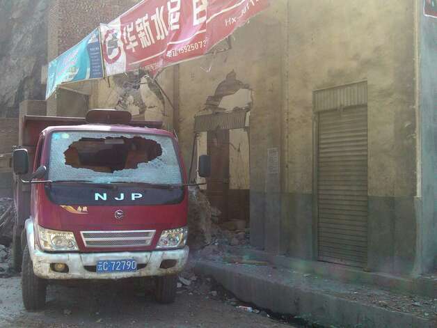 In this photo provided by Xinhua News Agency, a damaged truck parks by damaged houses in Luozehe Town, Yiliang County, southwest China's Yunnan Province on Friday. A series of earthquakes collapsed houses and triggered landslides in a remote mountainous part of southwestern China on Friday, killing dozens of people with the toll expected to rise. Damage was preventing rescuers from reaching some outlying areas, and communications were disrupted. (AP Photo/Xinhua, Zhou Hongpeng) Photo: Associated Press / SL