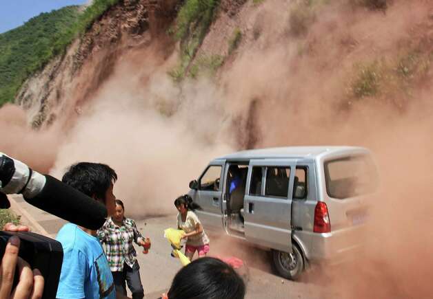 People run as fallen rocks land near their vehicle after the area was hit by earthquake in Zhaotong town, Yiliang County, southwest China's Yunnan Province, Friday, Sept. 7, 2012. A series of earthquakes collapsed houses and triggered landslides Friday in a remote mountainous part of southwestern China where damage was preventing rescues and communications were disrupted. At least 64 deaths have been reported. (AP Photo) CHINA OUT Photo: Associated Press / SL