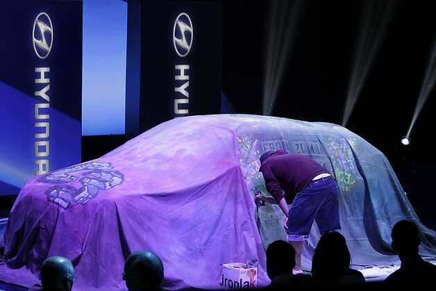 An artist spray paints the cover laying on top of the Hyundai Motor Co. Santa Fe during the LA Auto Show in Los Angeles, California, U.S., on Wednesday, Nov. 28, 2012. The LA Auto Show is open to the public Nov. 30 through Dec. 9. Photo: Jonathan Alcorn, Bloomberg / SF