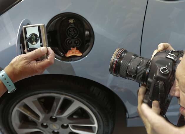 Members of the media photograph the charging port on the Chevy Spark EV during it's world debut at the LA Auto Show in Los Angeles, Wednesday, Nov. 28, 2012. (AP Photo/Chris Carlson) Photo: Chris Carlson, Associated Press / SF