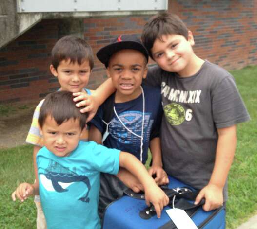 Isaiah Foster, a Fresh Air Fund child from Brooklyn, N.Y., wearing baseball cap, stands last summer with members of the Blanco host family from Westport in their front yard: Lucas in front, Nicolas to the left of Foster, and Kristian to Foster's right. Photo: Contributed Photo