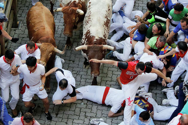 An Alcurrucen's ranch fighting bull (L) collides with runners entering the bullring during the second day of the San Fermin Running Of The Bulls festival, on July 7, 2013 in Pamplona, Spain. The annual Fiesta de San Fermin, made famous by the 1926 novel of US writer Ernest Hemmingway 'The Sun Also Rises', involves the running of the bulls through the historic heart of Pamplona, this year for nine days from July 6-14. Photo: Pablo Blazquez Dominguez, Getty Images / 2013 Getty Images