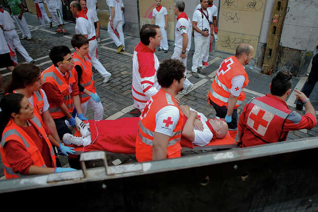 Medical services carry a man after Dolores Aguirre's ranch fighting bulls passed along Curva Estafeta during the third day of the San Fermin Running Of The Bulls festival, on July 8, 2013 in Pamplona, Spain. The annual Fiesta de San Fermin, made famous by the 1926 novel of US writer Ernest Hemmingway 'The Sun Also Rises', involves the running of the bulls through the historic heart of Pamplona for nine days from July 6-14. Photo: Pablo Blazquez Dominguez, Getty Images / 2013 Getty Images