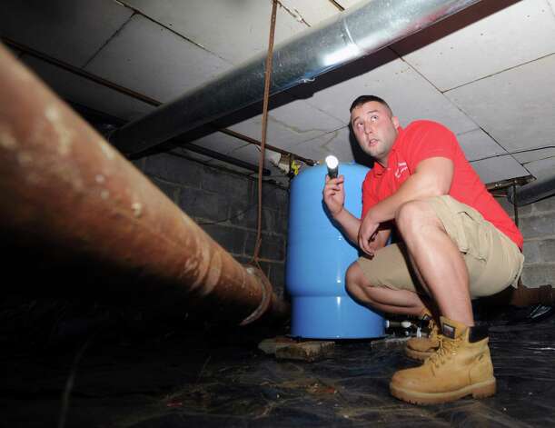 Neil Scott inspects piping in a crawl-space at a McArthur Lane home in Stamford, Tuesday, August 13, 2013. Scott's father, G. Neil Scott is the owner of Scott and Scott Home Inspection Services Inc., of Stamford. Photo: Bob Luckey / Greenwich Time