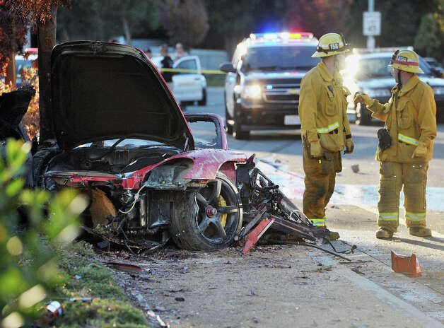 First responders gather evidence near the wreckage of a Porsche sports car that crashed into a light pole on Hercules Street near Kelly Johnson Parkway in Valencia on Saturday, Nov. 30, 2013. A publicist for actor Paul Walker says the star of the "Fast &amp; Furious" movie series has died in a car crash north of Los Angeles. He was 40. Photo: Dan Watson, Associated Press / The Santa Clarita Valley Signal