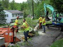 New Milford, Conn. town workers clear debris from Van Car Road left from a rain storm the night before, in New Milford, Conn., Wednesday, May 28, 2014.
