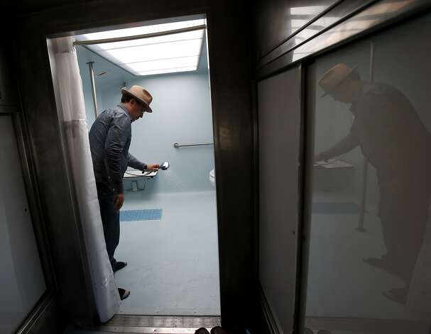 Lava Mae staffer Michael McMorrow cleans a shower stall in the new Lava Mae bus, currently a pilot project. Photo: Brant Ward, San Francisco Chronicle