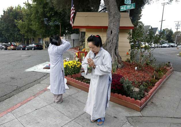 Vina Vo (left) and Kieu Do pray at sunrise near a Buddhist shrine at 11th Avenue and East 19th Street in Oakland. Photo: Paul Chinn, The Chronicle