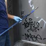 Jaime Najera Jr., paints over graffiti left by celebrants on a Mission Street business in San Francisco, Calif. on Thursday, Oct. 30, 2014. The celebration turned ugly when crowds became unruly and vandalized several businesses and vehicles after the Giants beat the Kansas City Royals in the World Series.