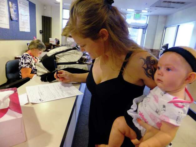 In this July 16, 2012, photo, Laura Fritz, 27, left, with her daughter Adalade Goudeseune fills out a form at the Jefferson Action Center, an assistance center in the Denver suburb of Lakewood. Both Fritz grew up in the Denver suburbs a solidly middle class family, but she and her boyfriend, who has struggled to find work, and are now relying on government assistance to cover food and $650 rent for their family. The ranks of America's poor are on track to climb to levels unseen in nearly half a century, erasing gains from the war on poverty in the 1960s amid a weak economy and fraying government safety net. Census figures for 2011 will be released this fall in the critical weeks ahead of the November elections. (AP Photo/Kristen Wyatt) Photo: Kristen Wyatt / AP