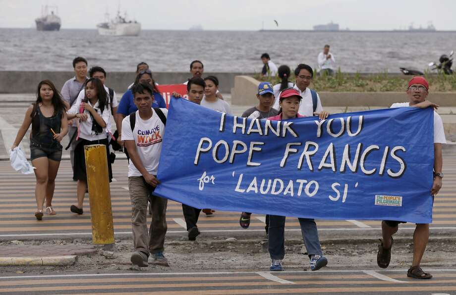 Environmental activists carry a banner as they march towards a Roman Catholic church to coincide with Pope Francis' encyclical on climate change Thursday, June 18, 2015 in Manila, Philippines. In a high-level, 190-page document released Thursday, Francis describes ongoing human damage to nature as "one small sign of the ethical, cultural and spiritual crisis of modernity." The solution, he says, will require self-sacrifice and a "bold cultural revolution" worldwide. (AP Photo/Bullit Marquez) Photo: Bullit Marquez, Associated Press