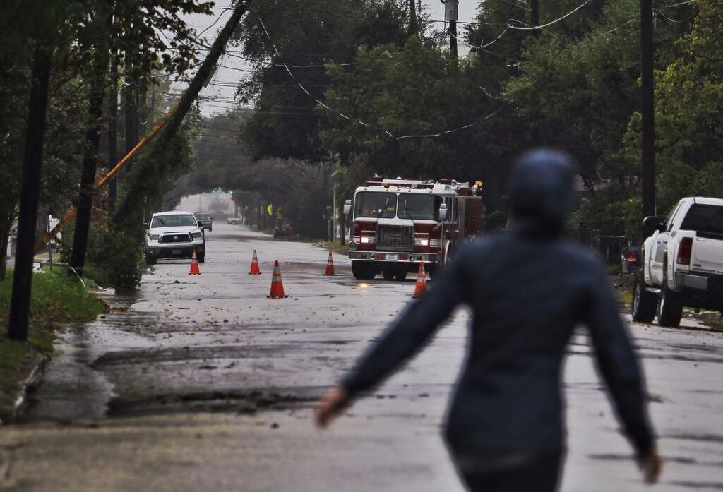A woman walks past a downed power line on Crockett St. near downtown Houston as the rain continues.
