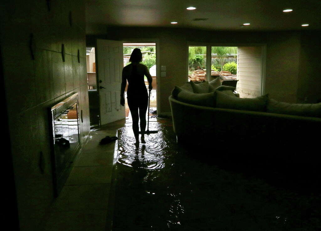 Meital Harari pushes water out of the back door at her Meyerland home, Monday, April 18, 2016, in Houston. Her family rode out the storm at a nearby house because her daughter has nightmares from the Memorial Day floods. Photo: Jon Shapley, Houston Chronicle / © 2015  Houston Chronicle