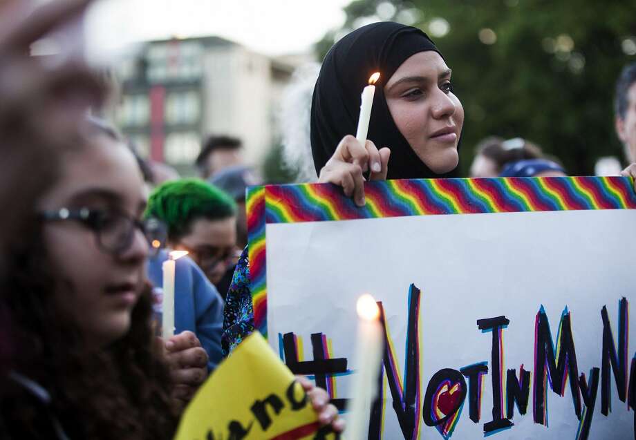 Zuleyha Ozonder, who is Muslim, holds a candle and a sign that references the hashtag "#NotInMyName" to show that many in the Islamic faith support the LGBTQ community during a vigil at Cal Anderson Park in Seattle. Photo: Lindsey Wasson, Associated Press