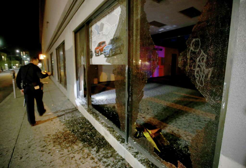 An Oakland police officer checks out damage after a window was broken by protesters at a car dealership in downtown Oakland, Calif., on Wednesday, Nov. 9, 2016. President-elect Donald Trump’s victory set off multiple protests. (Jane Tyska/Bay Area News Group via AP) Photo: Jane Tyska, AP / THE OAKLAND TRIBUNE/BAY AREA NEWS GROUP/DIGITAL FIRST MEDIA