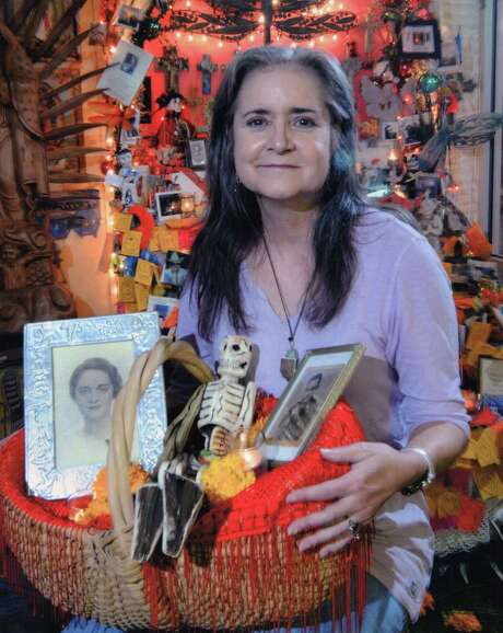 Mary Cerruti poses with a tribute she created for her parents as part of the annual Day of the Dead celebration at Casa Ramirez, a store where she occasionally worked. The store owners estimate the photo was taken around 2010. The basket contains images of her parents, a wood folk art skeleton, marigolds and small candles. Photo: Agapito Sanchez For Casa Ramirez, Courtesy Of Casa Ramirez