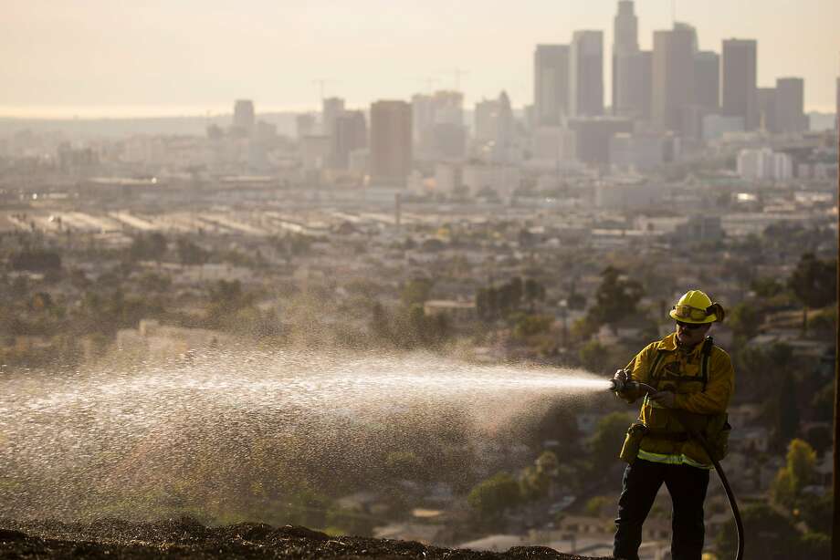 Firefighters work to put out smoldering patches of a fire that burned six acres of land at Ascot Hills Park in Los Angeles. Photo: Kent Nishimura, TNS