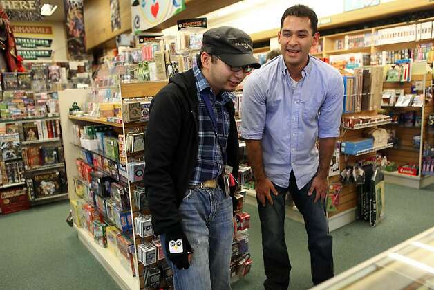 Guido Abenes (left), a 25-year-old who is autistic, checks out cards at a game store in Berkeley with his social mentor, Ben Nomura-Weingrow. Photo: Liz Hafalia, The Chronicle / SF