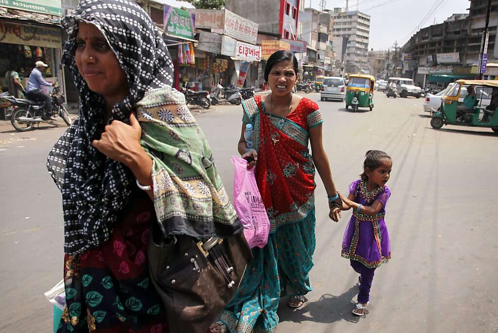 While still in pain from a cesarean section, Manisha Parmar and daughter Urvashi (right) walk through the streets in Anand, India, before catching a tuk-tuk ride back home to Khambhat, Monday, June 3, 2013. Usha Parmar, Raman's cousin who recruited Manisha into surrogacy, is in the foreground. Photo: Nicole Fruge, The Chronicle