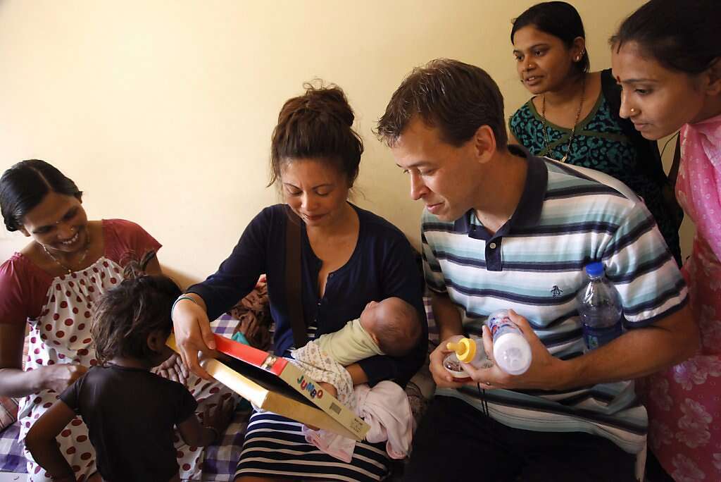 Jennifer Benito-Kowalski (center) and Steve Kowalski look at gifts for baby Kyle from surrogate Manisha Parmar (left) as two former surrogates look on at the Akanksha Infertility Clinic in Anand, India, Saturday, June 1, 2013. Parmar gave Kyle baby clothes and a tiny silver bracelet. The wristlet is a customary gift for newborns in India. Photo: Nicole Fruge, The Chronicle