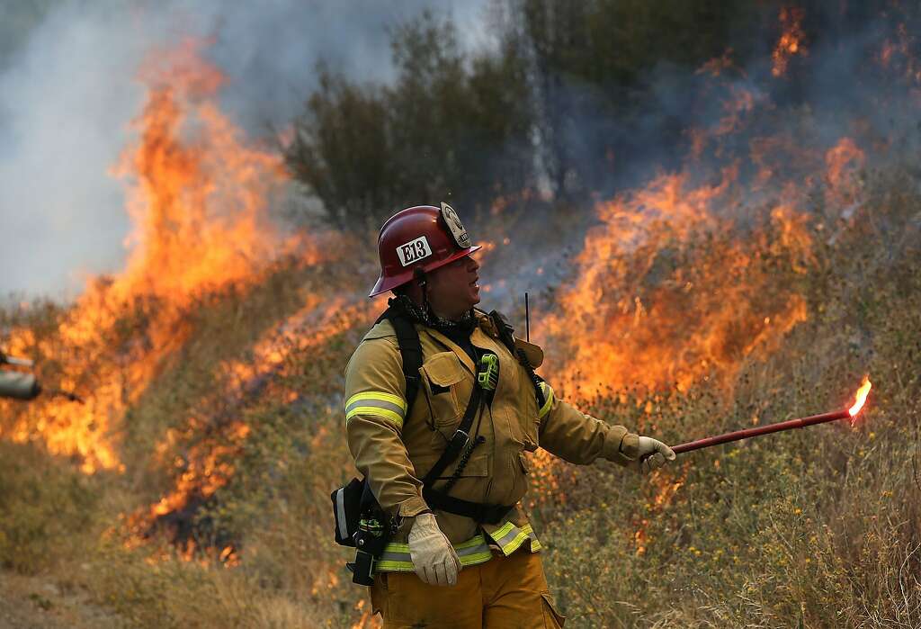A Long Beach Fire Department fire captain uses a flare to burn dry grass during a backfire operation to head off the Rocky Fire on August 3, 2015 near Clearlake, California. Nearly 3,000 firefighters are battling the Rocky Fire that has burned over 60,000 acres has forced the evacuation of 12,000 residents in Lake County. The fire is currently 12 percent contained and has destroyed at least 14 homes. 6,300 homes are threatened by the fast moving blaze. Photo: Justin Sullivan, Getty Images